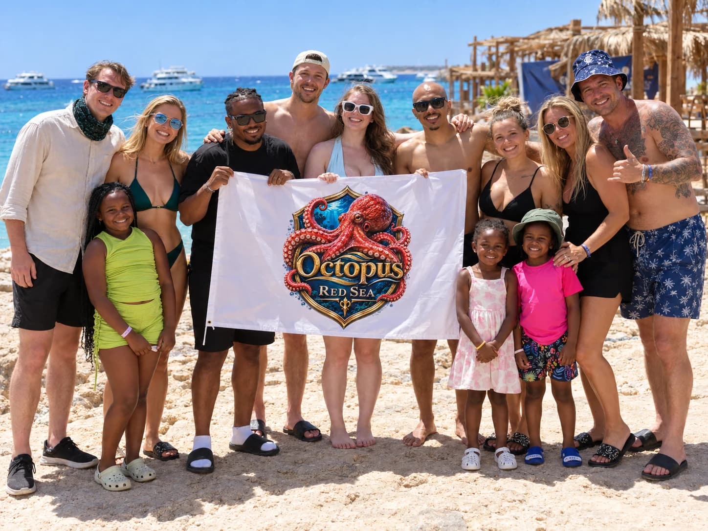 Group of adults and children standing on the beach holding a branded banner