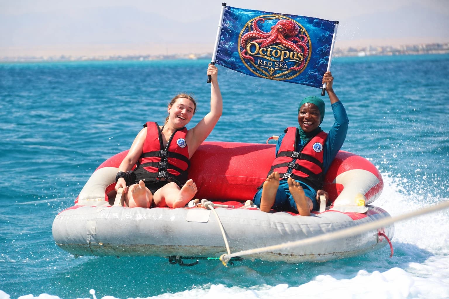 Two friends on an inflatable raft with an Octopus Red Sea branded banner
